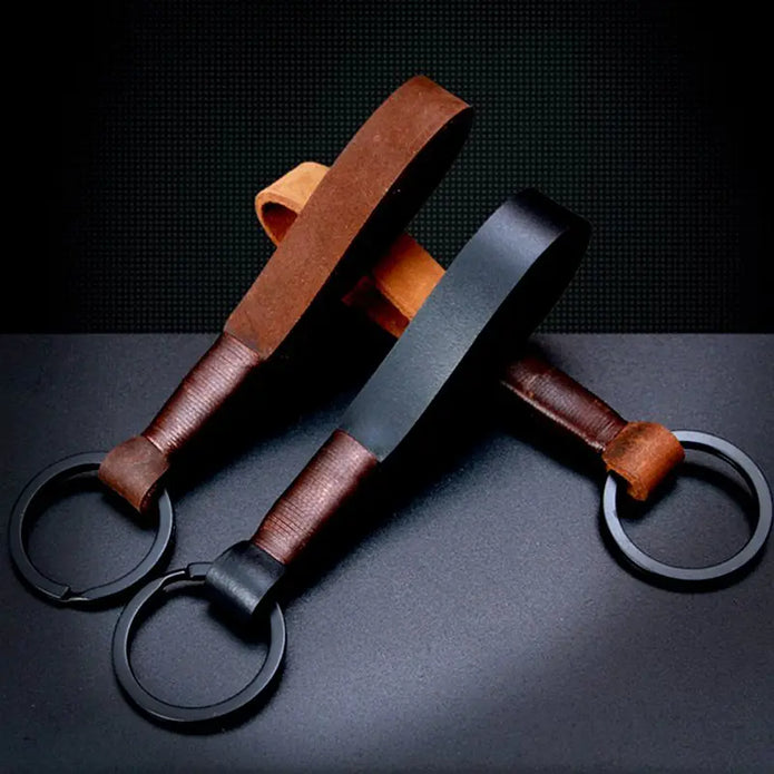 Three leather keychains with metal rings on a dark surface